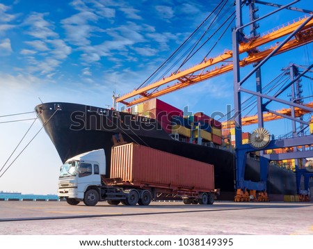 The container vessel  during discharging at an industrial port and move containers to container yard by trucks.