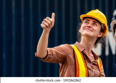 Container yard workers woman in yellow helmet smiling and thumb up with her collegue on second floor - Powered by Shutterstock