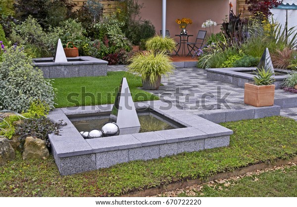 Containers of Carex grass and water\
features in a patio in a contemporary garden\
design