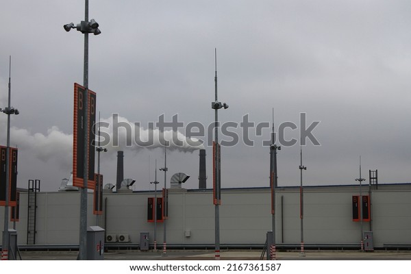 Contaminated Air Over Rooftop Vehicle Park\
With Smoking Stacks On\
Background