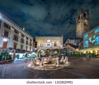 Contarini fountain on Piazza Vecchia square and Campanone tower in the old part of Bergamo, Italy at night.