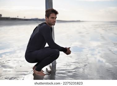 Contemplating going in for another wave. A handsome young man crouching down next to his seurfboard and looking at the ocean. - Powered by Shutterstock