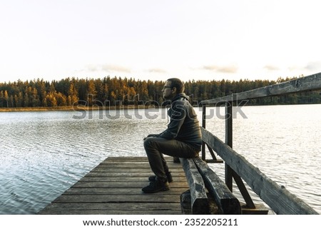 Similar – Man sitting by the river in fall