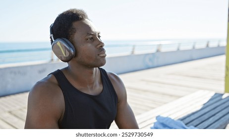 A contemplative african american man wearing headphones stands at the sunlit beachside promenade. - Powered by Shutterstock