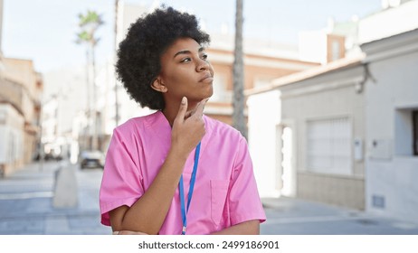 A contemplative african american woman in a pink uniform with a lanyard, standing against an urban backdrop. - Powered by Shutterstock