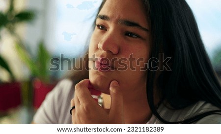 Contemplative Expression of an Ethnically Diverse Asian Young Woman in her 20s Pondering Deeply with Hand on Chin