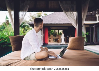 Contemplative male software developer thinking about graphic design for website during remote working at comfortable terrace, Caucaisan blogger with digital netbook doing distance job outdoors