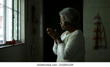 A Contemplative Senior Black Woman Praying To God At Home