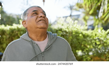 Contemplative senior man gazing upward in a sunlit verdant park setting - Powered by Shutterstock