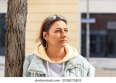 Contemplative woman outdoors in urban setting wearing sunglasses - Powered by Shutterstock