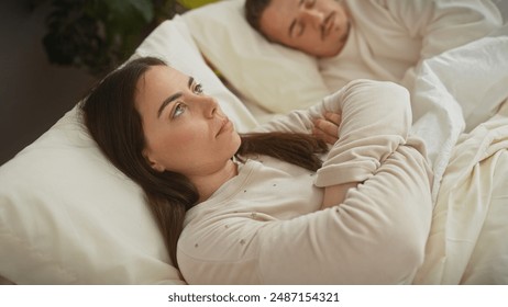 A contemplative woman and a sleeping man sharing a peaceful moment together in a bedroom setting. - Powered by Shutterstock