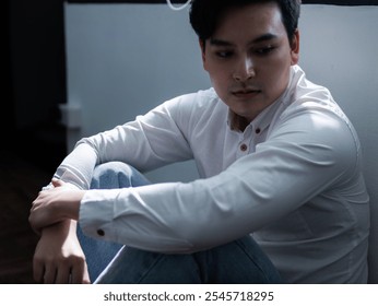 Contemplative young man in white shirt indoor setting portrait photography dimly lit environment emotional reflection - Powered by Shutterstock