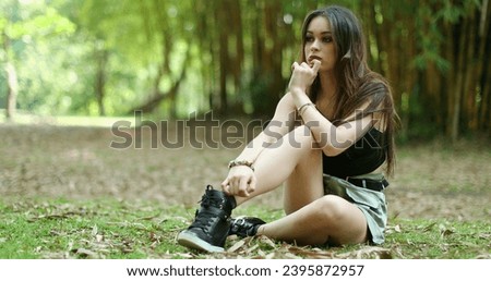 Contemplative young woman sitted in outdoor park thinking. Thoughtful girl in 20s thinking