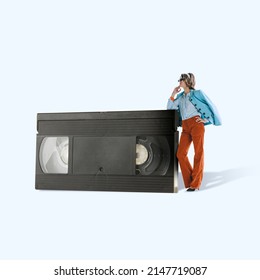 Contemporary art collage. Stylish young woman leaning at retro film cassette. Vintage fashion, retro lifestyle. Combination of times. Concept of fashion, style, movies, past. Copy space for ad