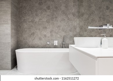 Contemporary bathroom with white bathtub, oval washbasin and hexagonal tiles