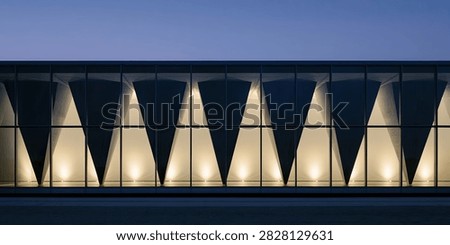 A contemporary building facade features triangular architectural elements casting dramatic shadows and illuminated interiors, creating a striking geometric pattern against the twilight sky.