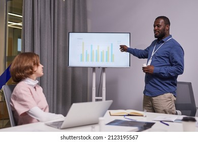 Contemporary Confident Medical Expert Pointing At Interactive Screen With Charts While Analyzing Data During Presentation At Seminar