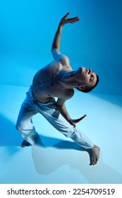 Contemporary dance style. Young artistic man dancing contemp, experimental dance over blue studio background. Flexible artist. Concept of art, body aesthetics, motion, action, inspiration. - Shutterstock ID 2254709519