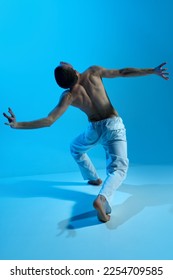 Contemporary dance style. Young artistic man dancing contemp, experimental dance over blue studio background. Beauty of movements. Concept of art, body aesthetics, motion, action, inspiration. - Shutterstock ID 2254709585