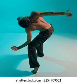 Contemporary dance style. Young man, professional contemp dancer, performing, dancing over blue, cyan studio background. Modern. Concept of art, body aesthetics, motion, action and inspiration. - Shutterstock ID 2254709521