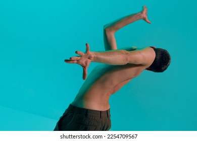 Contemporary dance style. Young shirtless flexible man dancing modern dance over blue, cyan studio background. Self-expression, lifestyle. Concept of art, body aesthetics, motion, action, inspiration. - Shutterstock ID 2254709567