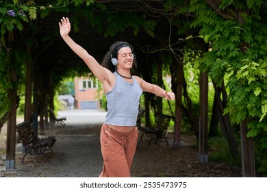 A contemporary dancer moves gracefully in a park, immersed in music through headphones, blending artistry with nature's serenity. - Powered by Shutterstock