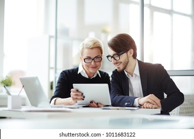 Contemporary Employees With Digital Tablet Watching Video Conference Or Online Seminar While Sitting In Office