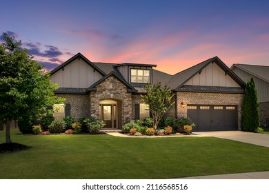 Contemporary Home Exterior with Colorful Sunset. Green Grass, Brick and Stacked Stone, Meticulous Landscaping, Warm and Inviting House.