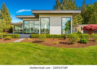 Contemporary Home Exterior On Lakeshore With Flat Roof And Large Feature Windows