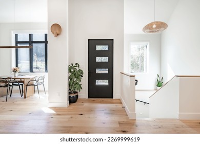 Casa contemporánea con mobiliario mínimo y decoración de madera clara escaleras suelo de paredes blancas grandes ventanas con marcos negros y estilo sencillo