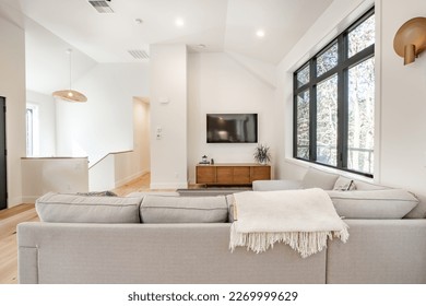 Contemporary home with minimal furnishings and decor light wood floor stairs white walls large windows with black frames and simple style - Powered by Shutterstock