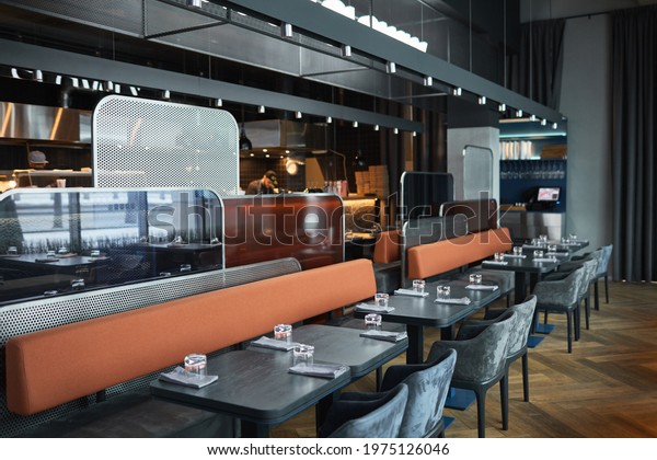 Contemporary interior of\
bistro cafe in black color with long sofas separated with metallic\
and glass panels