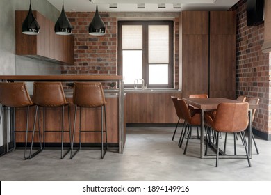 Contemporary Interior Design Of Light Spacious Dinning Room Including Brown Wooden Furniture With Bar Stools At Counter And Soft Comfortable Chairs At Table With Cement Effect In Loft Style