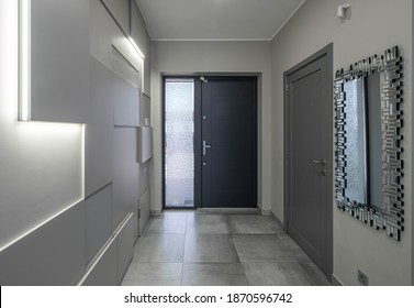 Contemporary Interior Of Entrance Hall In Luxury Apartment. Modern Design Of Wall. Iron Door. Mirror On Wall.