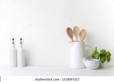 Contemporary kitchen background with kitchen utensils standing on white countertop, blank space for a text, front view