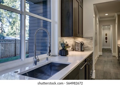 Contemporary Kitchen Design With Brown Kitchen Cabinets Paired With White Countertops And Glass Mosaic Tile Kitchen Backsplash. Northwest, USA
