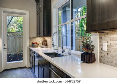 Contemporary Kitchen Design With Brown Kitchen Cabinets Paired With White Countertops And Glass Mosaic Tile Kitchen Backsplash. Northwest, USA
