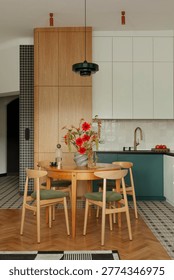 Contemporary kitchen and dining space featuring natural light, wooden table, olive green chairs, and a striking floral centerpiece. Stylish and inviting
