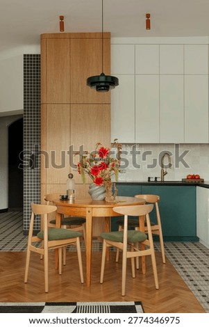 Contemporary kitchen and dining space featuring natural light, wooden table, olive green chairs, and a striking floral centerpiece. Stylish and inviting