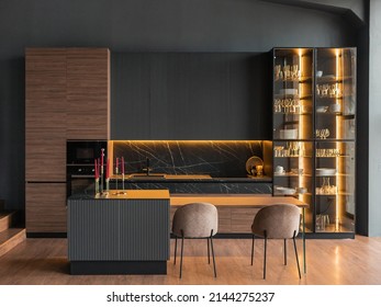contemporary kitchen in a modern style, wooden floor, dark grey interior.  kitchen island. cabinet with glass doors and lighting for wine glasses. upholstered chairs. countertops with black cabinets - Shutterstock ID 2144275237