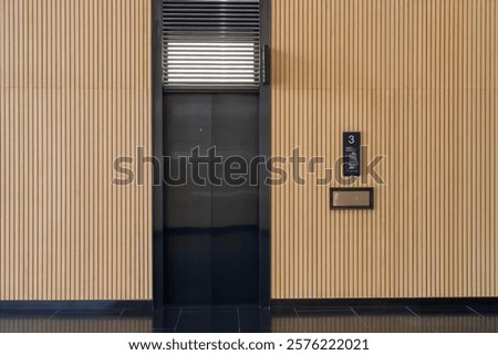 Contemporary lobby featuring  elevator door number 3 against vertical wooden panel walls, creating minimalist and stylish design in modern building, luxury with beautiful interior design