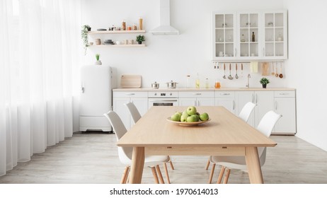 Contemporary minimalist interior of kitchen and dining room. White furniture with utensils and dinner table with chairs in Scandinavian style. Modern light design - Shutterstock ID 1970614013