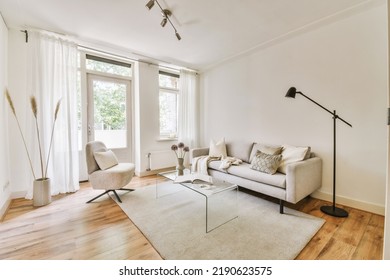 Contemporary minimalist style interior design of light studio apartment with wooden table and chairs in dining zone between open kitchen and living room with white walls and parquet floor