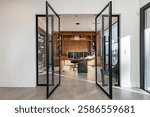 contemporary new construction modern home office design with wooden desk built in shelving large swinging glass doors with black steel trim wall of wine bottles view to dining room and entry foyer
