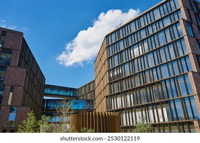 Contemporary office buildings with glass facades connected by skybridge. Modern architectural design under blue sky - Powered by Shutterstock