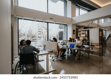 Contemporary office environment with a diverse group of colleagues, including a person in a wheelchair, engaged in work and discussions. - Powered by Shutterstock