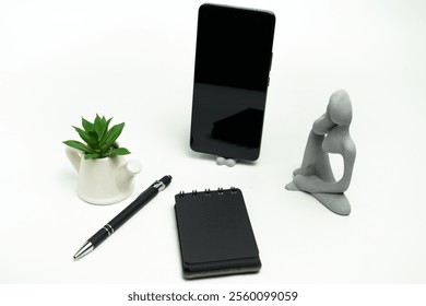 Contemporary smartphone and complementary items, including a charging adapter, USB cable, pen, and notebook, arranged on a minimalistic white surface.