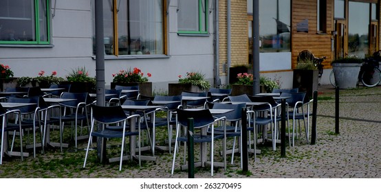 Contemporary Street Cafe With Steel Tables And Black Chairs On Paving Stone In Malmo, Sweden