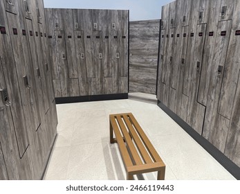 A contemporary styled locker room with wooden lockers, electronic locks, and a bench to sit on - Powered by Shutterstock