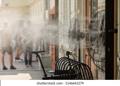 Contemporary system of fans with pulverizes spraying water with air and cooling air outdoors in hot summertime